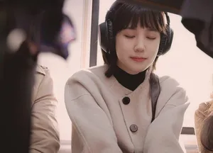 Woo Young-woo is on the train going to work. She's wearing noise canceling headphones and her eyes are closed. Her expression is serene and calm, even though the train seems crowded.